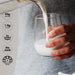 Person pouring creamy vanilla shake from Grass-fed Whey Protein Powder - Creamy Vanilla - 900g by Chief into glass