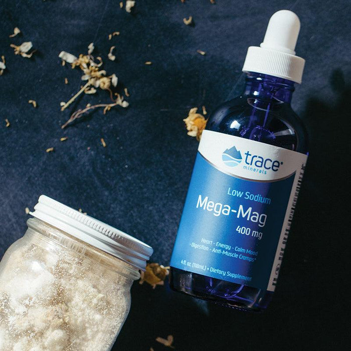 Low Sodium Mega-Mag - 400mg - 118ml by Trace Minerals in blue bottle with dropper on dark surface with jar and dried flowers