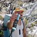 Man outdoors holding a Chief Organic Beef Stick - Sea Salt - 25g with backpack and trees in background