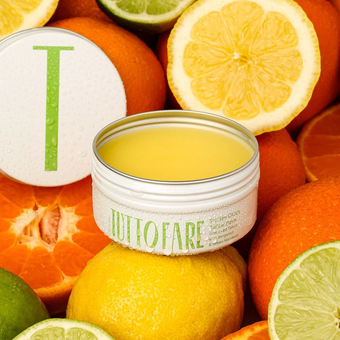 Open tin of Sicillian Citrus Tallow Balm - 70g by Tuttofare surrounded by sliced citrus fruits for skincare collection