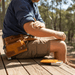 Man applying Tradie Tallow Balm - 40ml by Bare Bones Beauty on arm outdoors with work gear and balm tin nearby